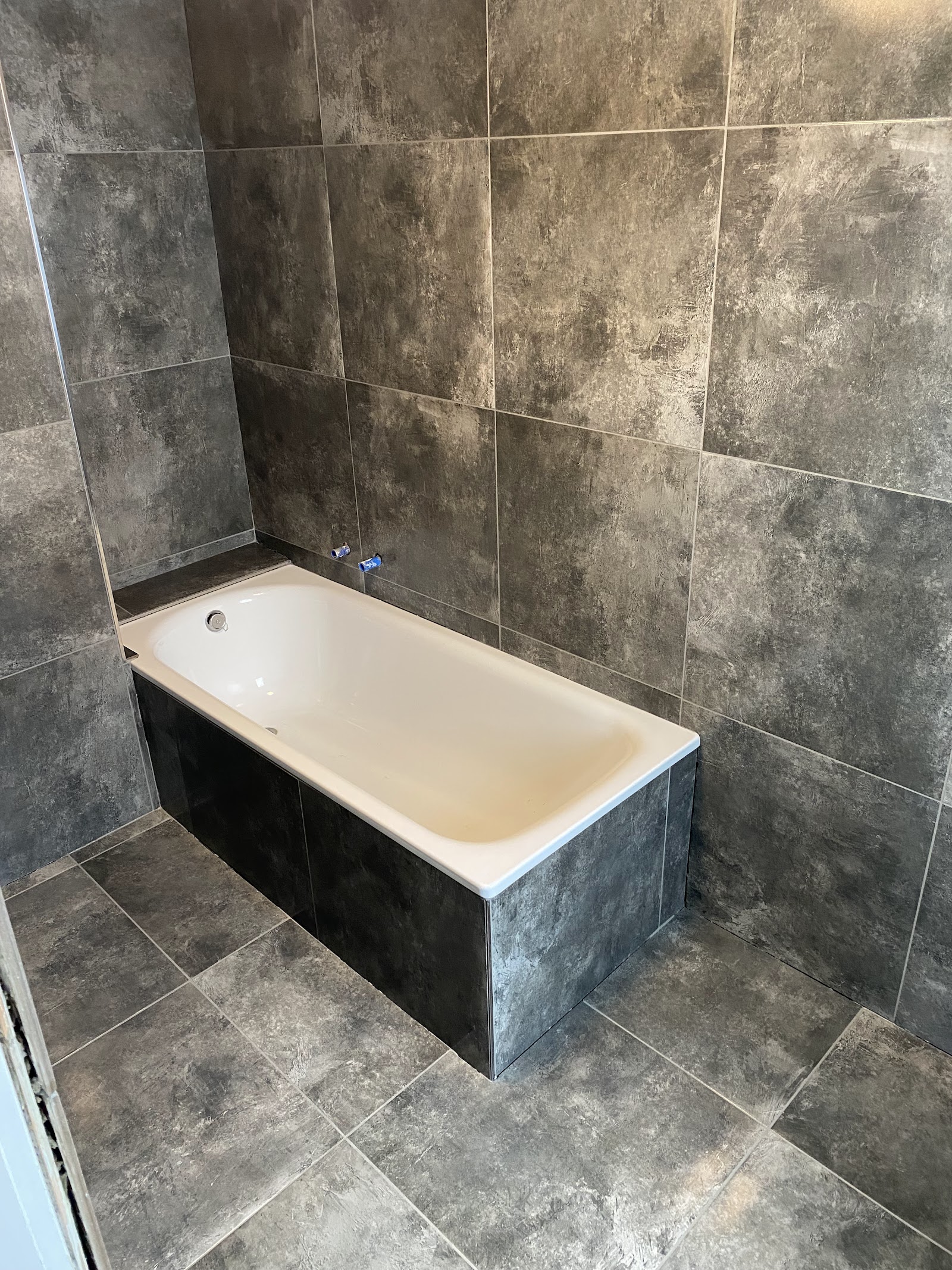 Badewanne mit großformatigen Fliesen in Betonoptik