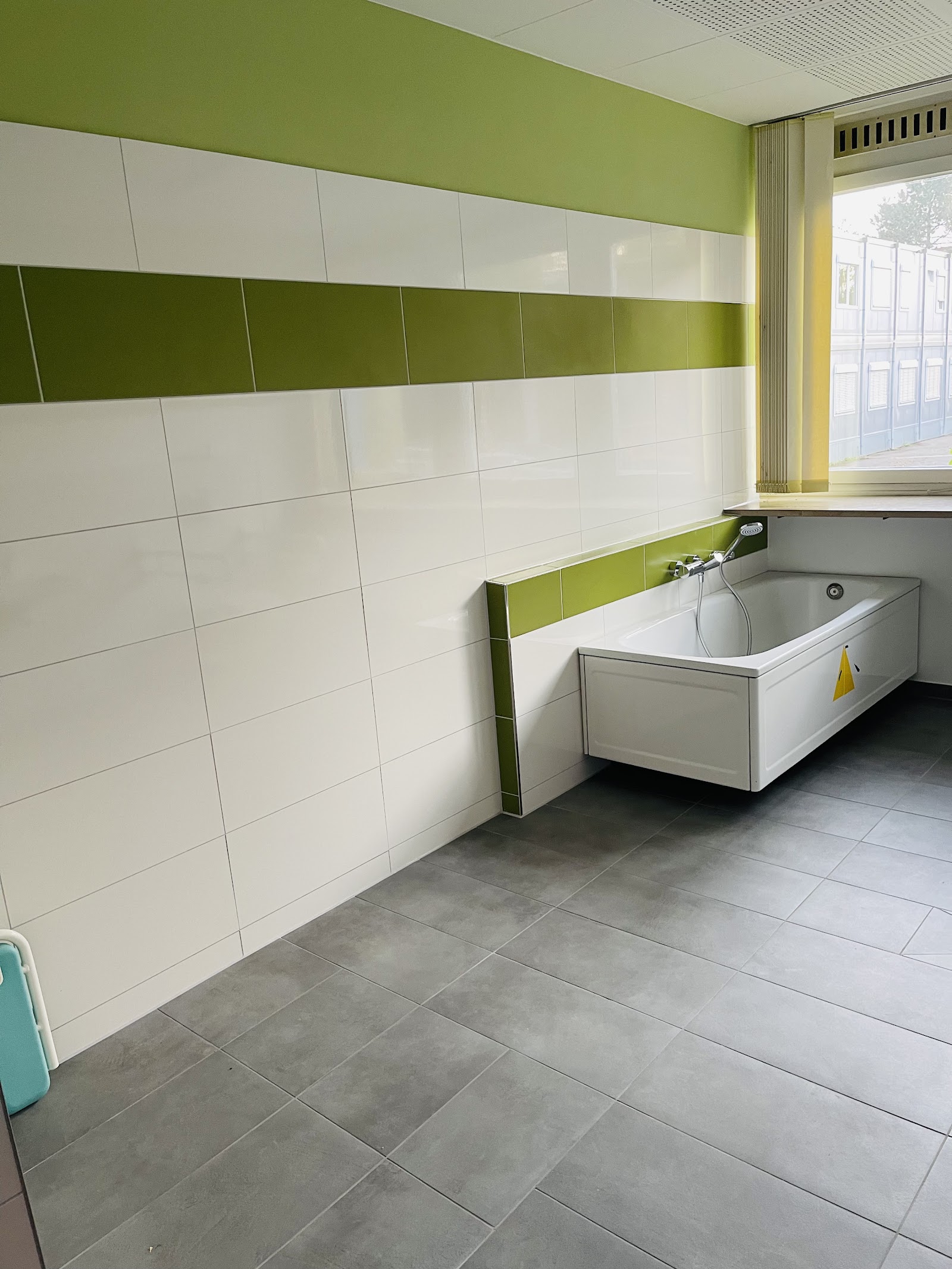 Badewanne mit weißen Fliesen und grünem Akzentstreifen